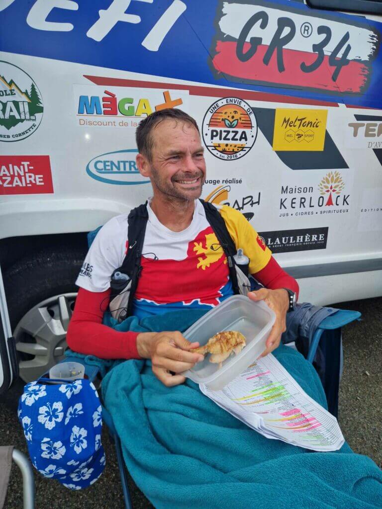 Erik Clavery assis devant son camping en train de manger lors d'un arrêt ravitaillement sur le record du GR34