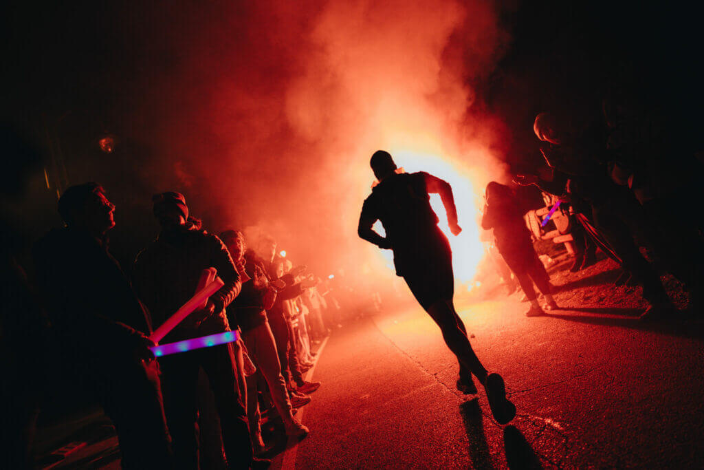 Ombre d'un coureur dans les fumigènes rouges des supporters